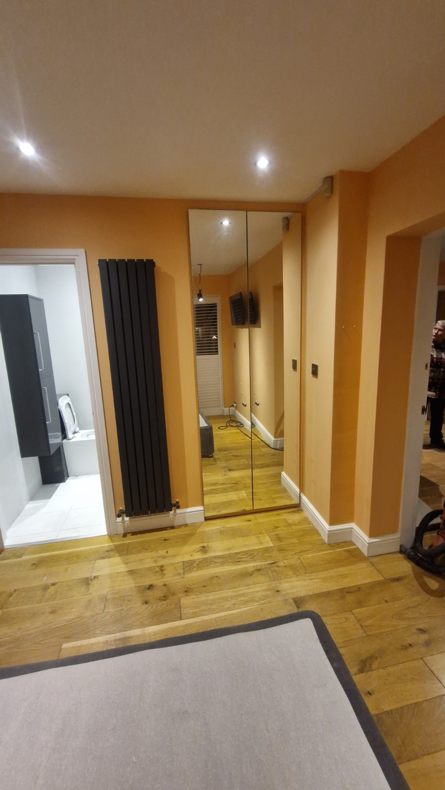 Finished painted bedroom with full-height mirrored wardrobe