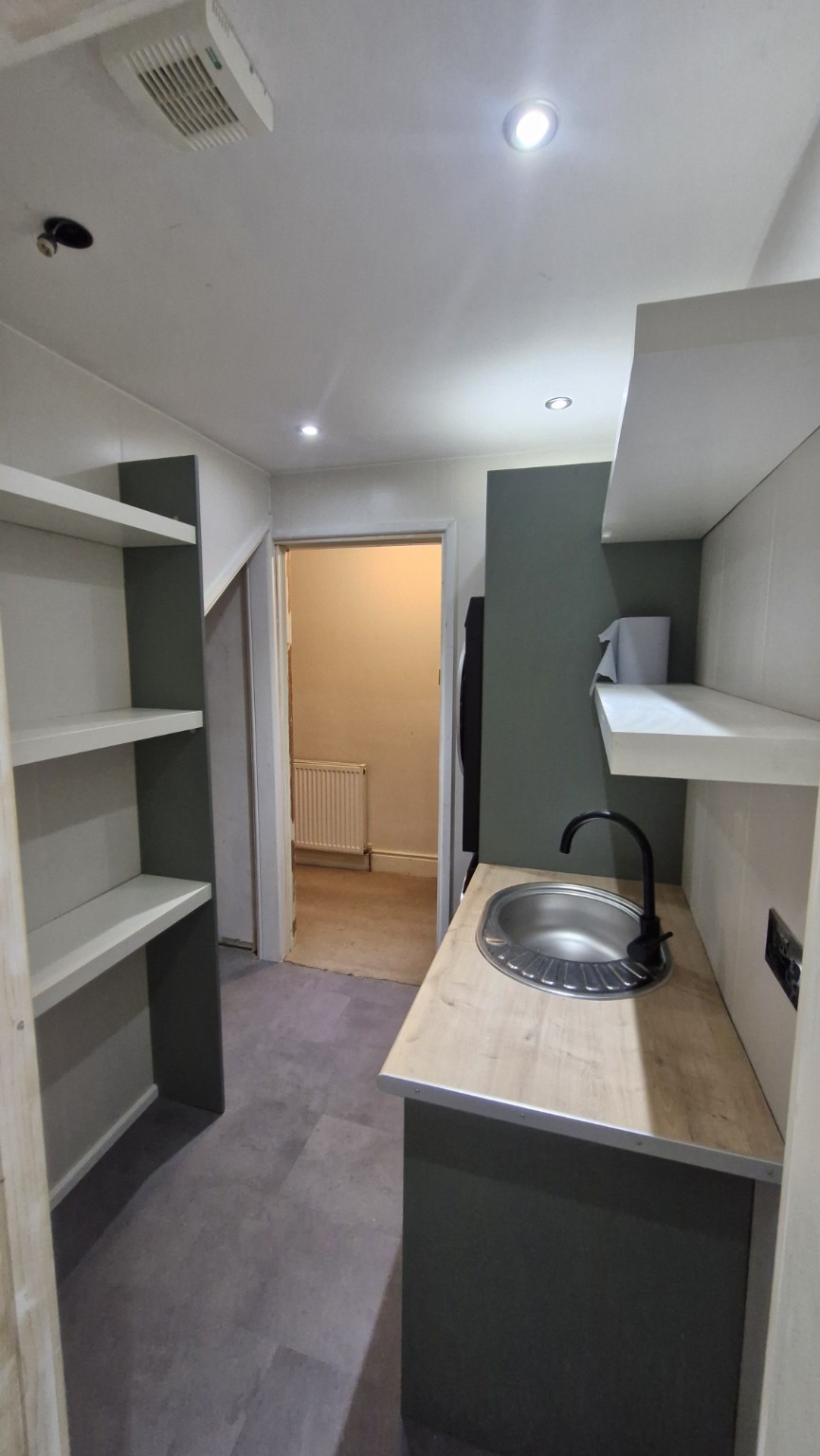 Finished utility room with sink and fitted shelving